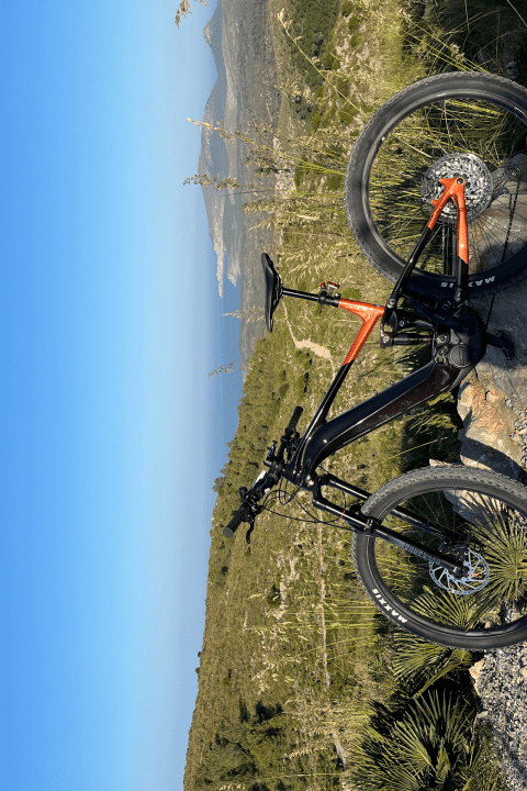 Mountain bike on gravel path with clear blue sky and distant hills.