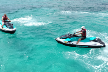 Two people jet skiing on clear turquoise water.